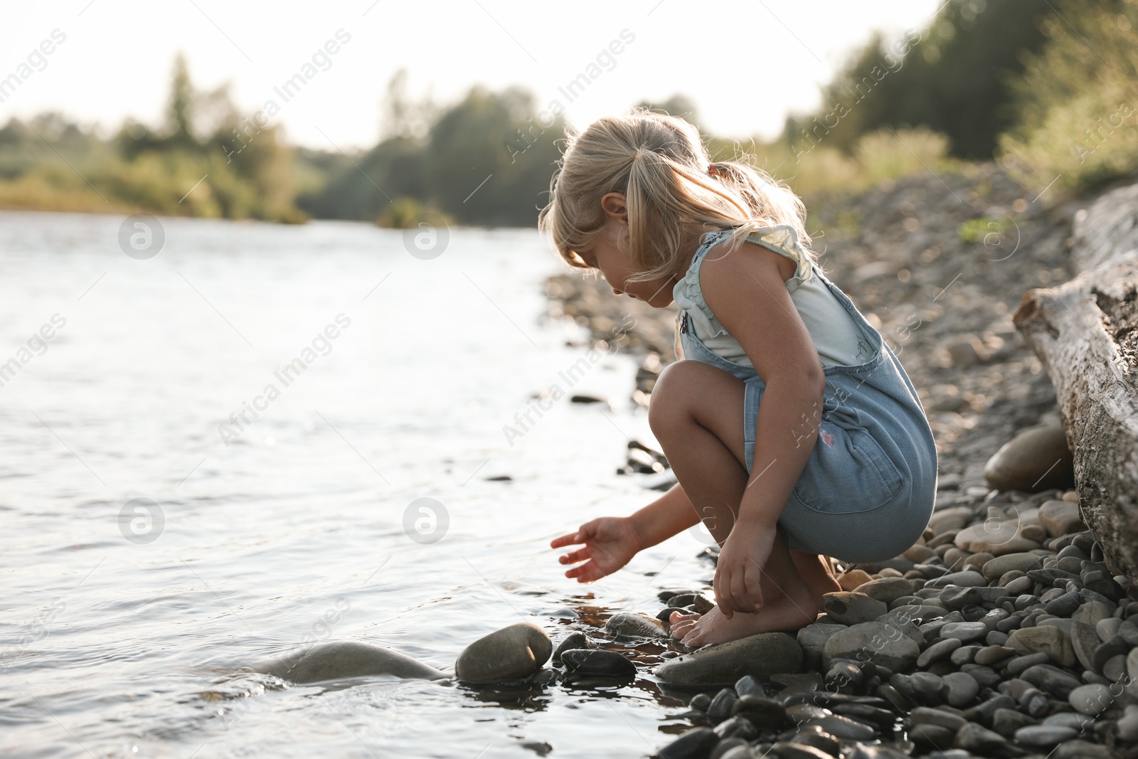 Photo of Cute little girl spending time on river. Child enjoying beautiful nature