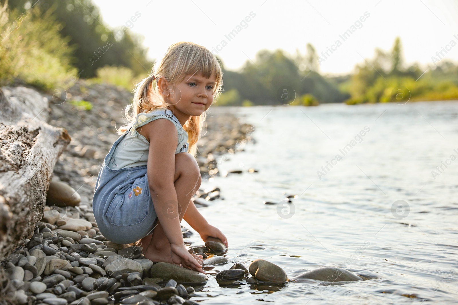 Photo of Cute little girl spending time on river. Child enjoying beautiful nature