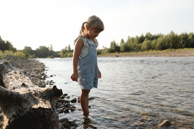 Photo of Cute little girl spending time on river. Child enjoying beautiful nature