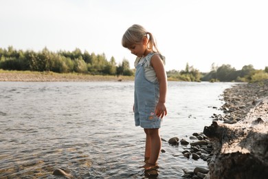 Photo of Cute little girl spending time on river. Child enjoying beautiful nature