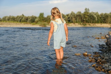 Cute little girl spending time on river. Child enjoying beautiful nature