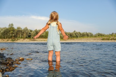 Photo of Cute little girl spending time on river. Child enjoying beautiful nature