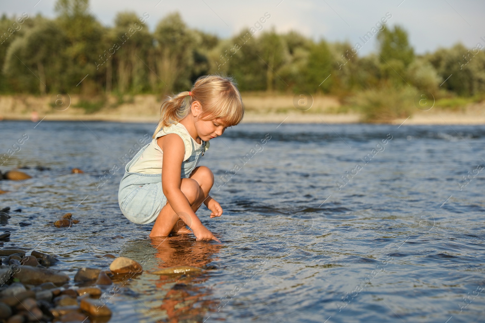 Photo of Cute little girl spending time on river. Child enjoying beautiful nature