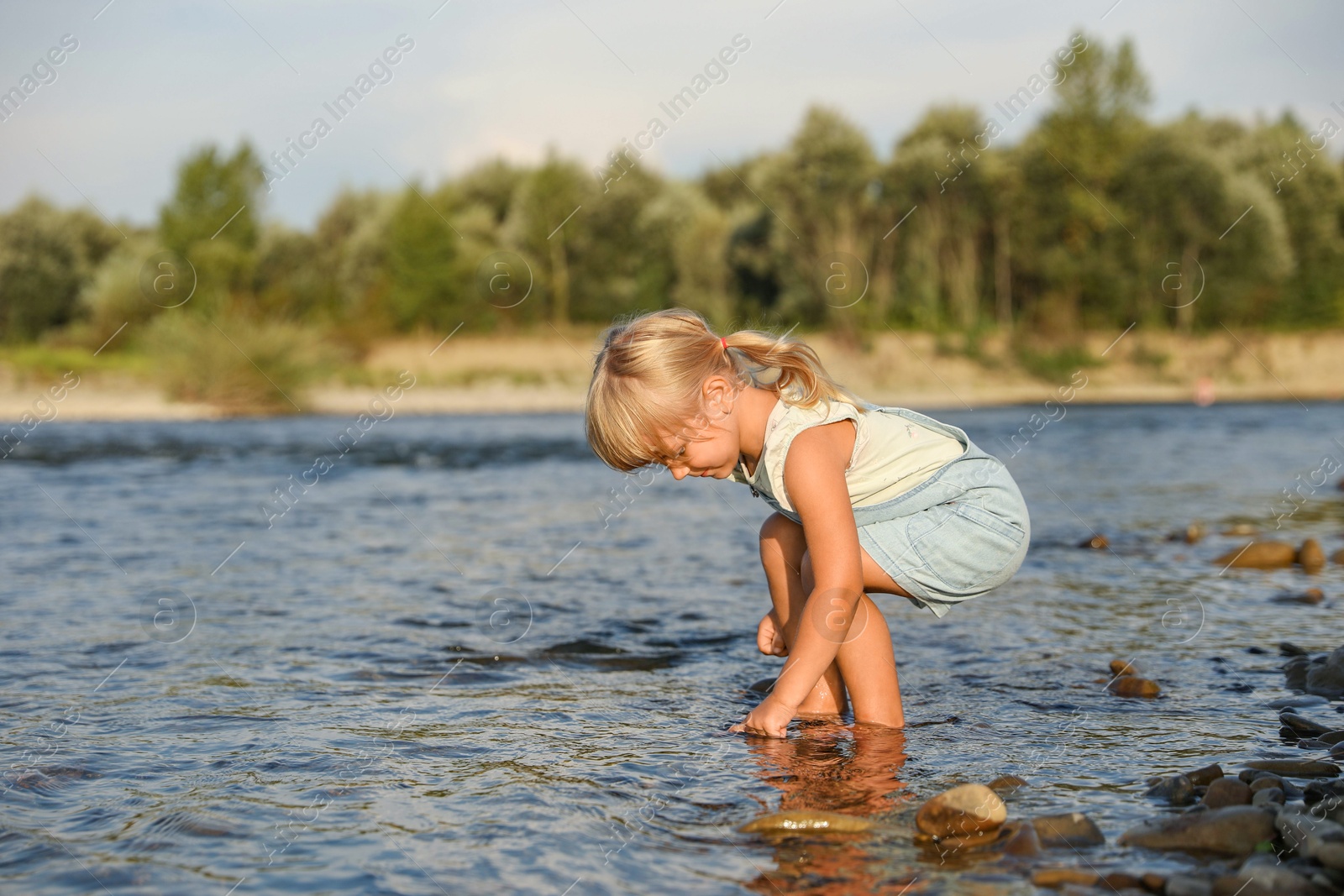 Photo of Cute little girl spending time on river. Child enjoying beautiful nature