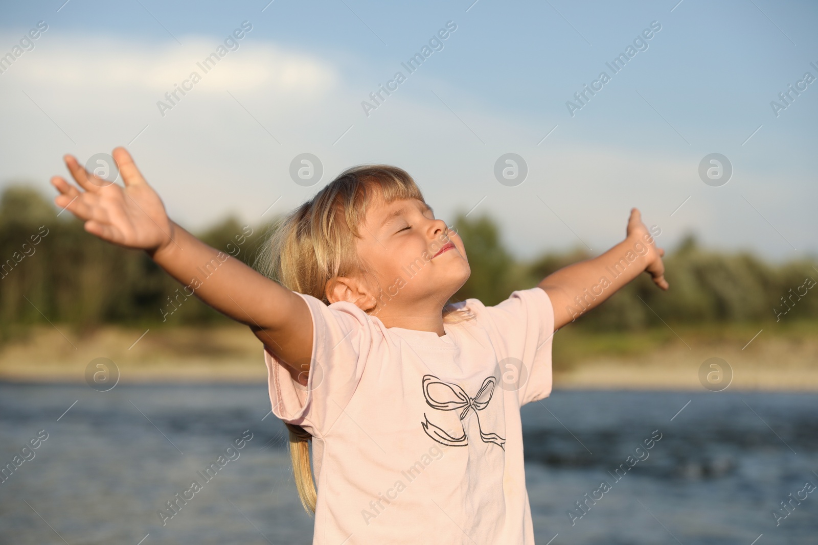 Photo of Cute little girl spending time near river. Child enjoying beautiful nature