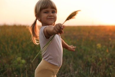 Photo of Cute little girl with plants at meadow. Child enjoying beautiful nature