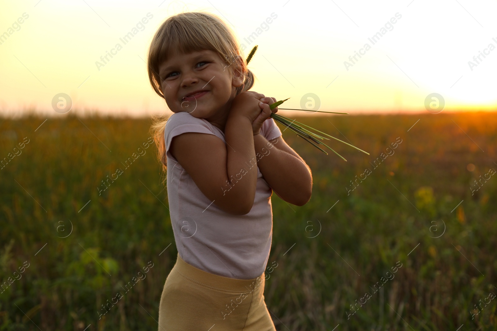 Photo of Cute little girl with plants at meadow. Child enjoying beautiful nature