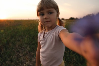 Photo of Cute little girl with flower outdoors at sunset. Child enjoying beautiful nature