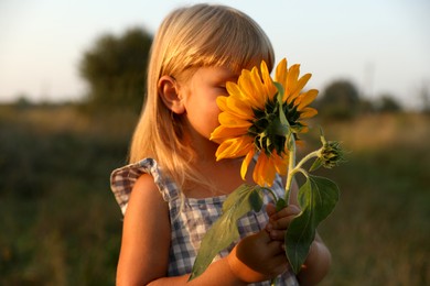 Photo of Little girl with sunflower at meadow. Child enjoying beautiful nature