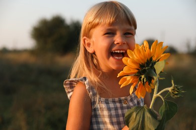 Photo of Little girl with sunflower at meadow. Child enjoying beautiful nature