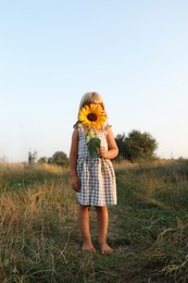 Photo of Little girl with sunflower at meadow. Child enjoying beautiful nature