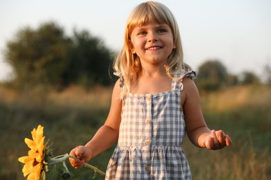 Photo of Little girl with sunflower at meadow. Child enjoying beautiful nature