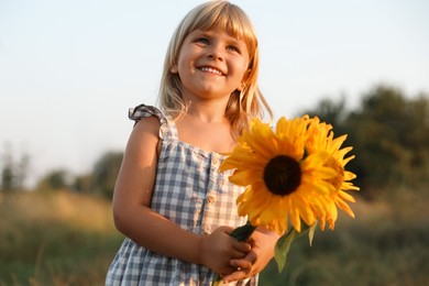 Photo of Little girl with sunflowers at meadow. Child enjoying beautiful nature