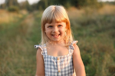 Photo of Happy little girl at meadow. Child enjoying beautiful nature