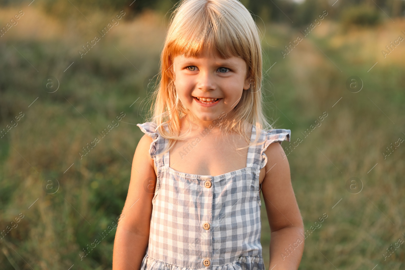 Photo of Happy little girl at meadow. Child enjoying beautiful nature