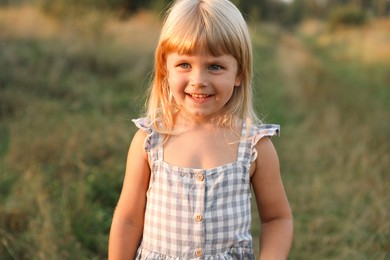 Photo of Happy little girl at meadow. Child enjoying beautiful nature