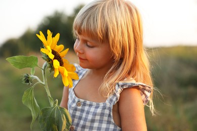 Photo of Little girl with sunflower at meadow. Child enjoying beautiful nature