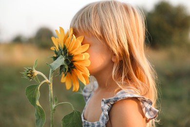 Photo of Little girl with sunflower at meadow. Child enjoying beautiful nature