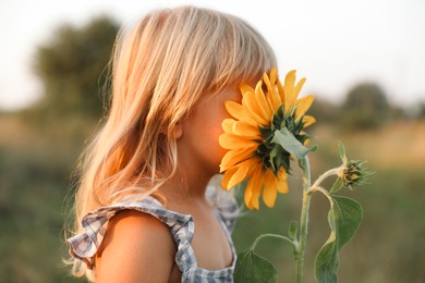 Photo of Little girl with sunflower at meadow. Child enjoying beautiful nature