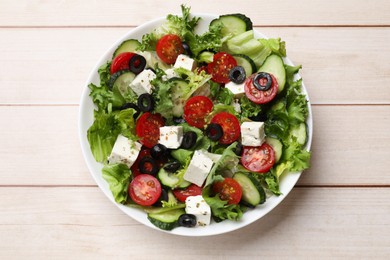 Photo of Delicious salad with feta cheese on white wooden table, top view