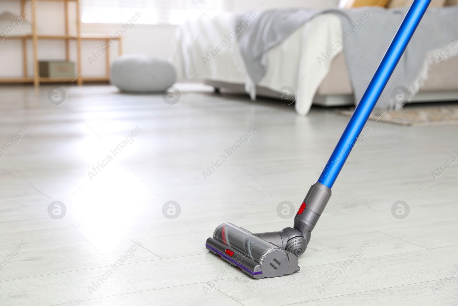 Photo of Cleaning floor with cordless vacuum cleaner indoors, closeup. Space for text