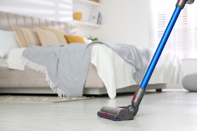 Photo of Cleaning floor with cordless vacuum cleaner indoors, closeup. Space for text