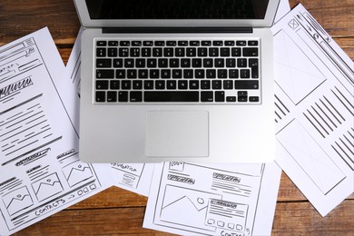 Developing UI design. Sketches of website wireframes and laptop on wooden table, top view