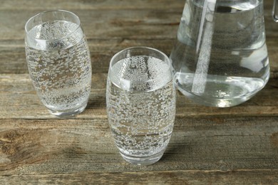 Photo of Soda water in glasses and jug on wooden table