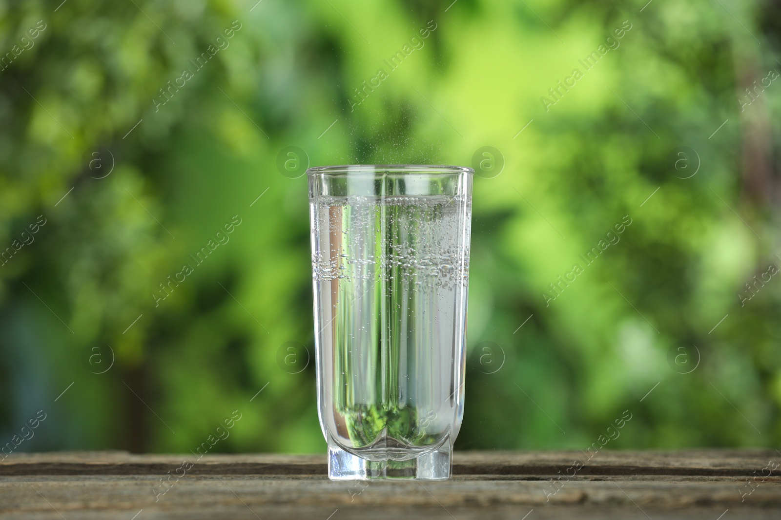 Photo of Soda water in glass on wooden table outdoors