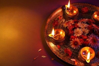 Photo of Diwali celebration. Diya lamps and beautiful flowers on color background, space for text