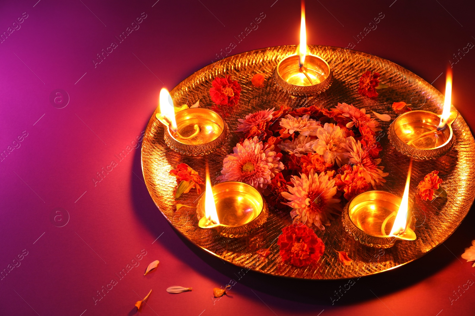 Photo of Diwali celebration. Diya lamps and beautiful flowers on color background