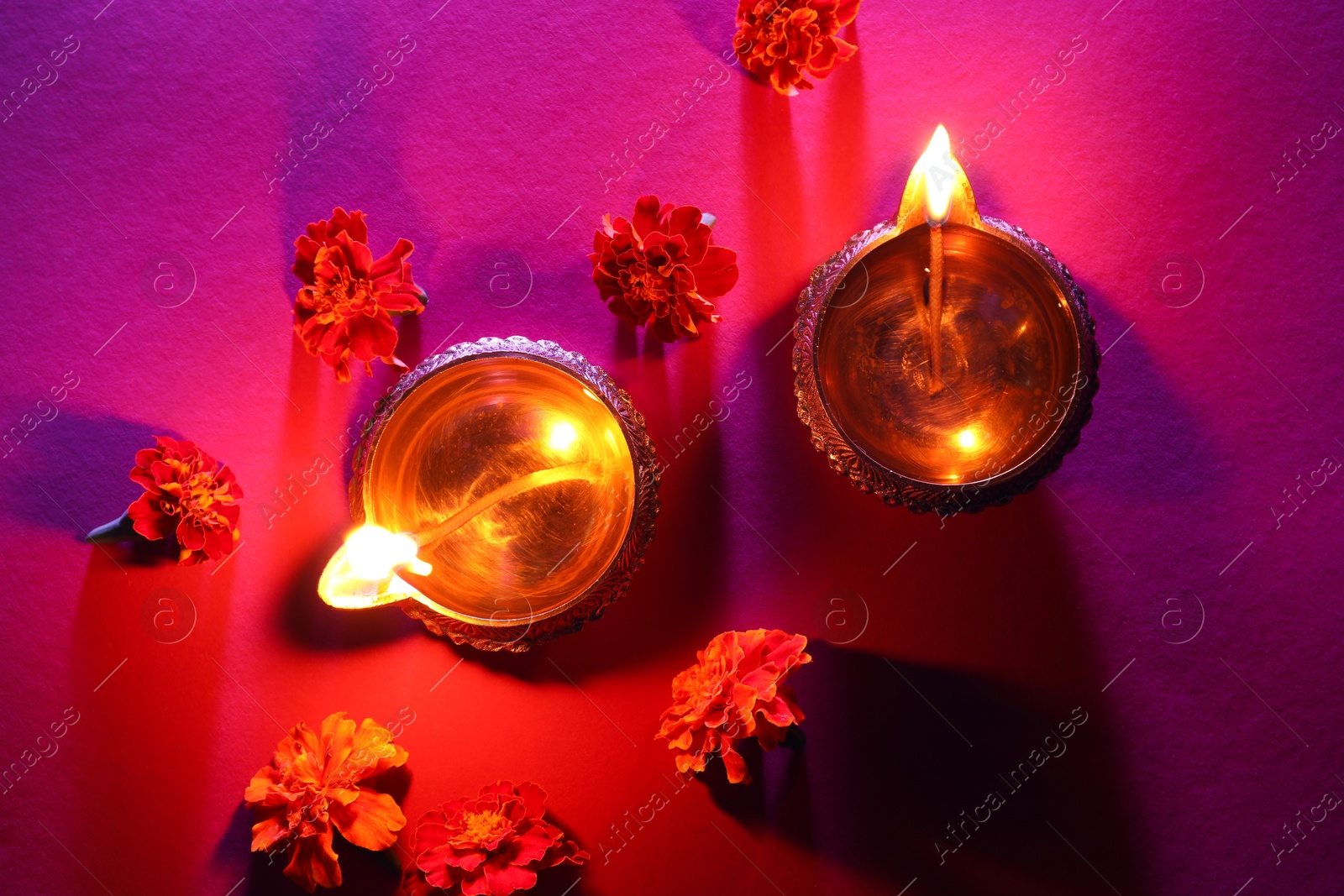 Photo of Diwali celebration. Diya lamps and beautiful flowers on color background, flat lay