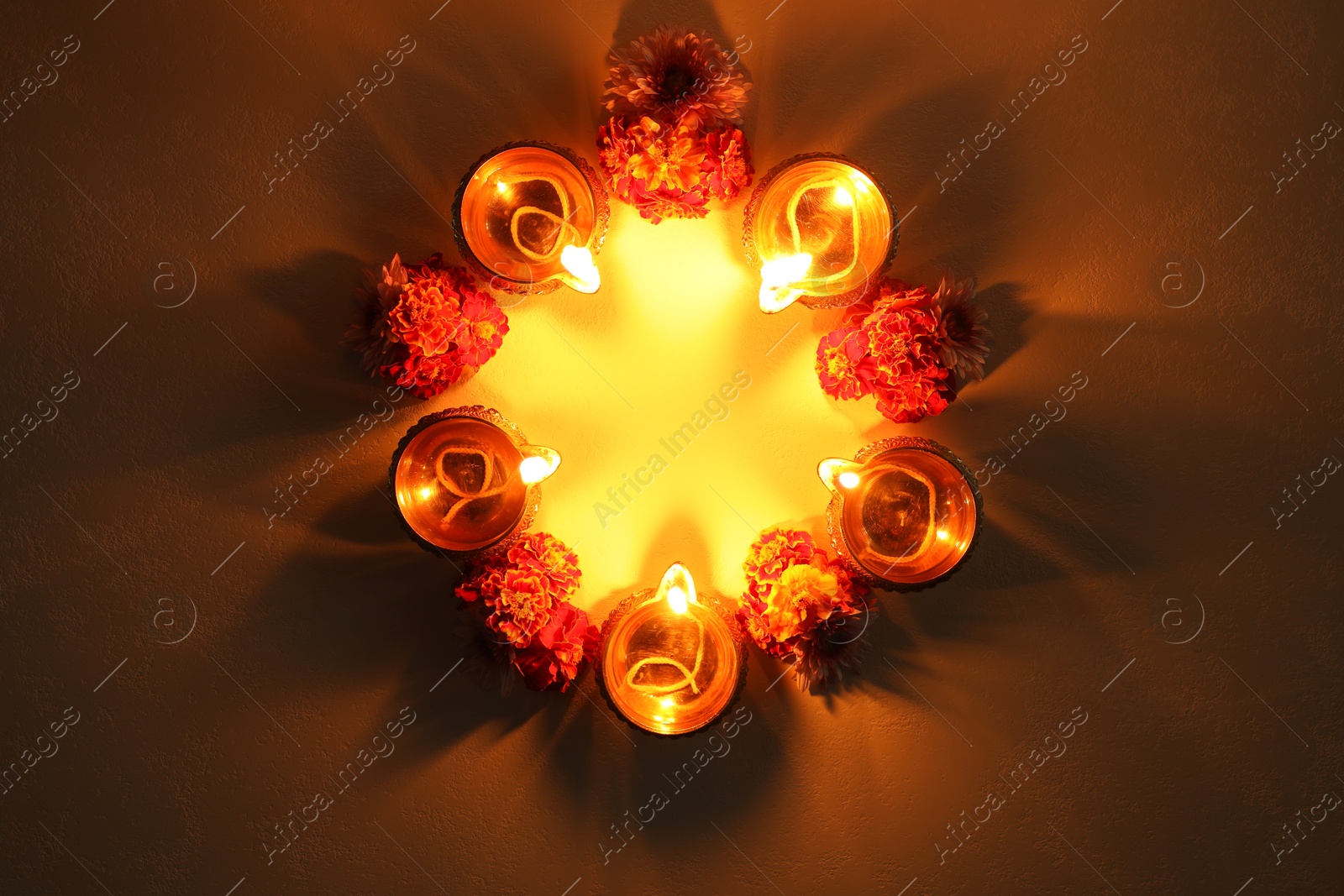 Photo of Diwali celebration. Diya lamps and beautiful flowers on dark textured surface, flat lay. Space for text