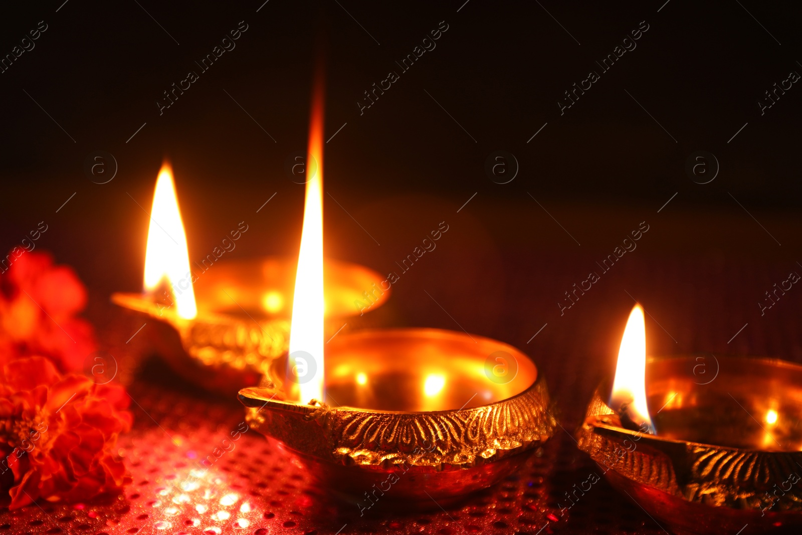 Photo of Diwali celebration. Diya lamps and beautiful flowers on dark background, closeup