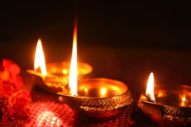 Photo of Diwali celebration. Diya lamps and beautiful flowers on dark background, closeup