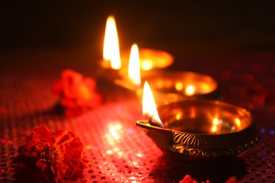 Photo of Diwali celebration. Diya lamps and beautiful flowers on dark background, closeup