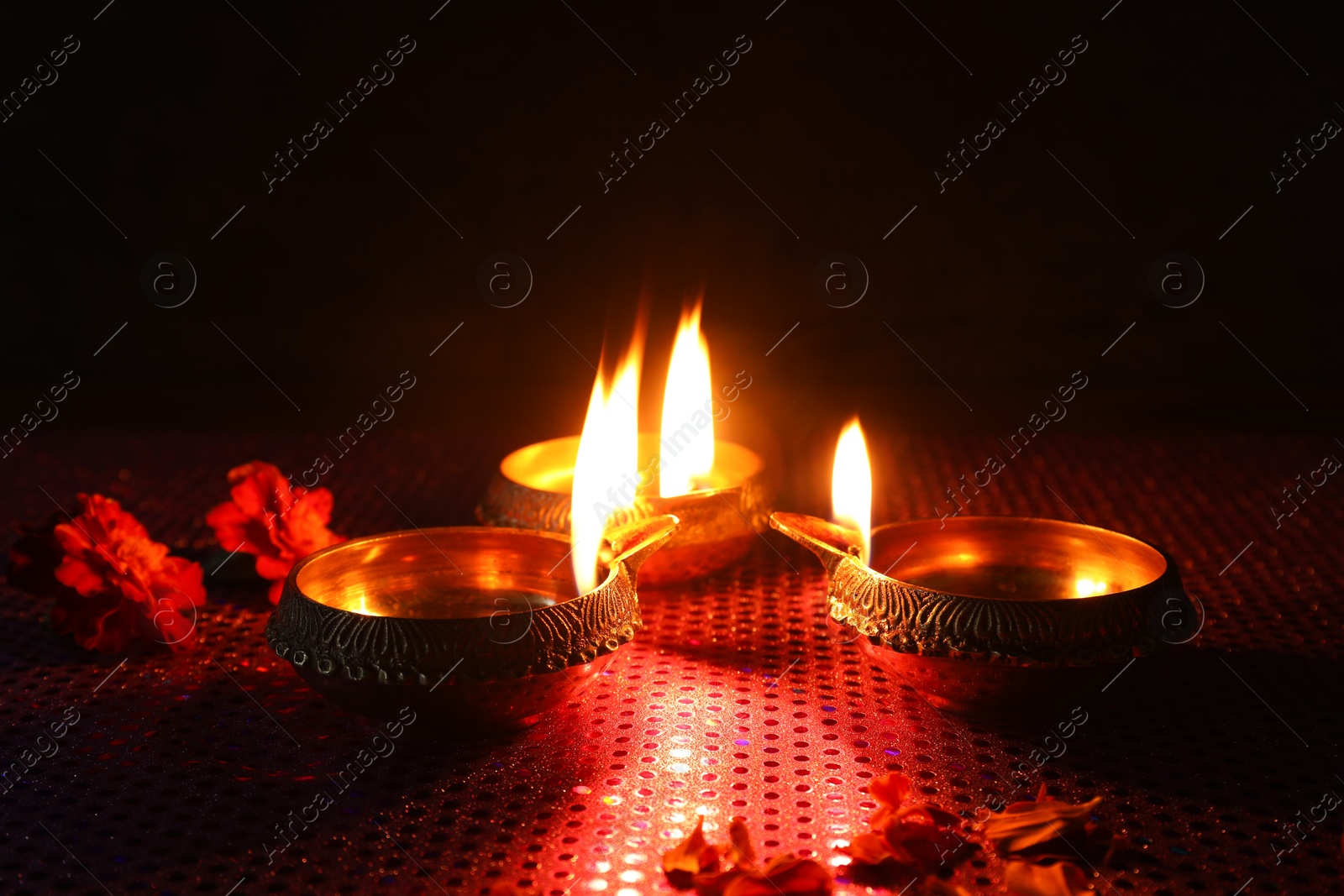 Photo of Diwali celebration. Diya lamps and beautiful flowers on dark background, closeup