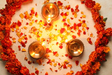 Photo of Diwali celebration. Diya lamps and beautiful flowers on light background, top view