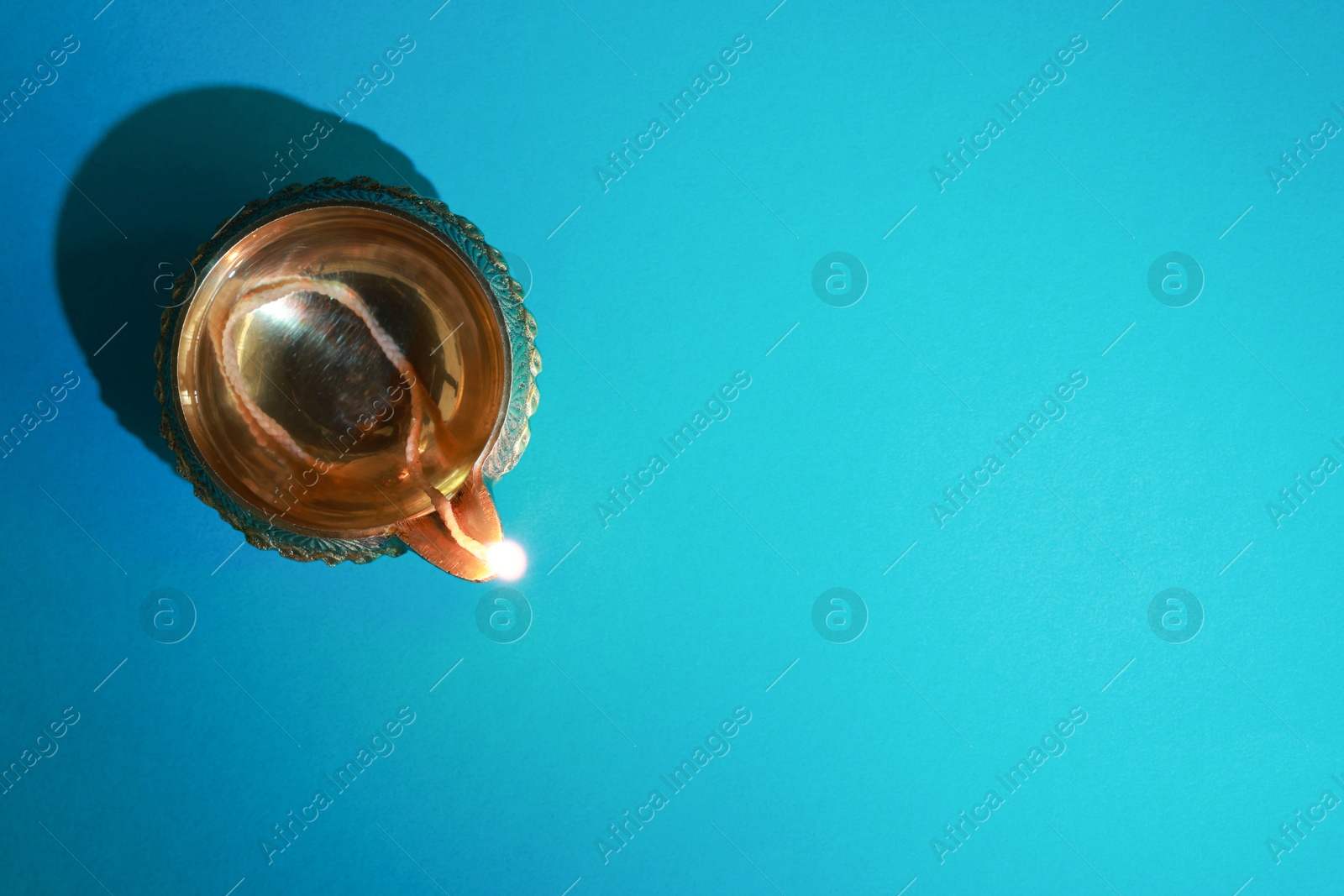 Photo of Diwali celebration. Diya lamp on teal background, top view. Space for text