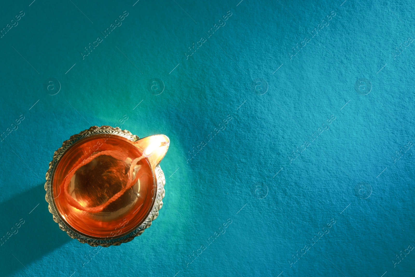 Photo of Diwali celebration. Diya lamp on teal background, top view. Space for text