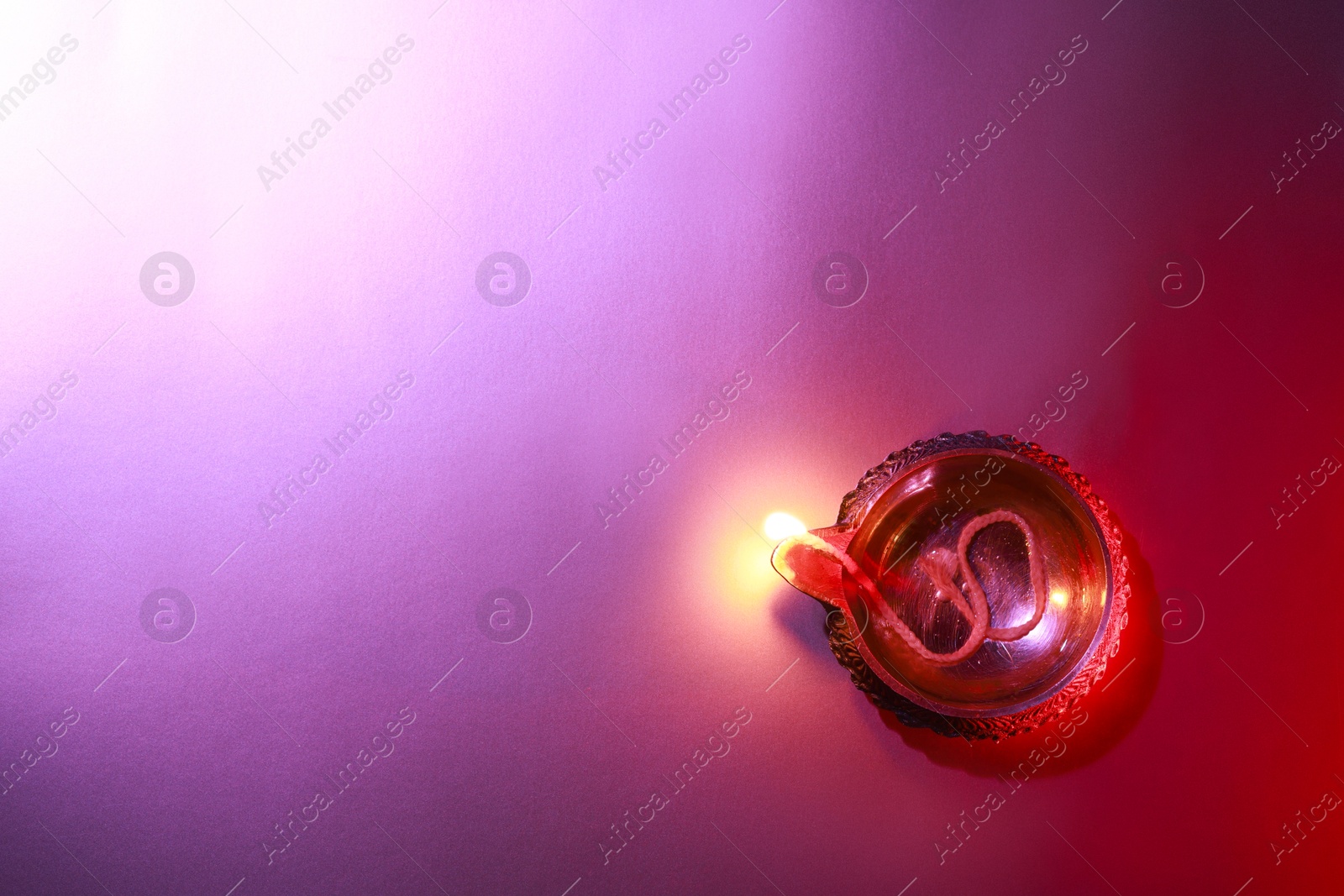 Photo of Diwali celebration. Diya lamp on purple background, top view. Space for text