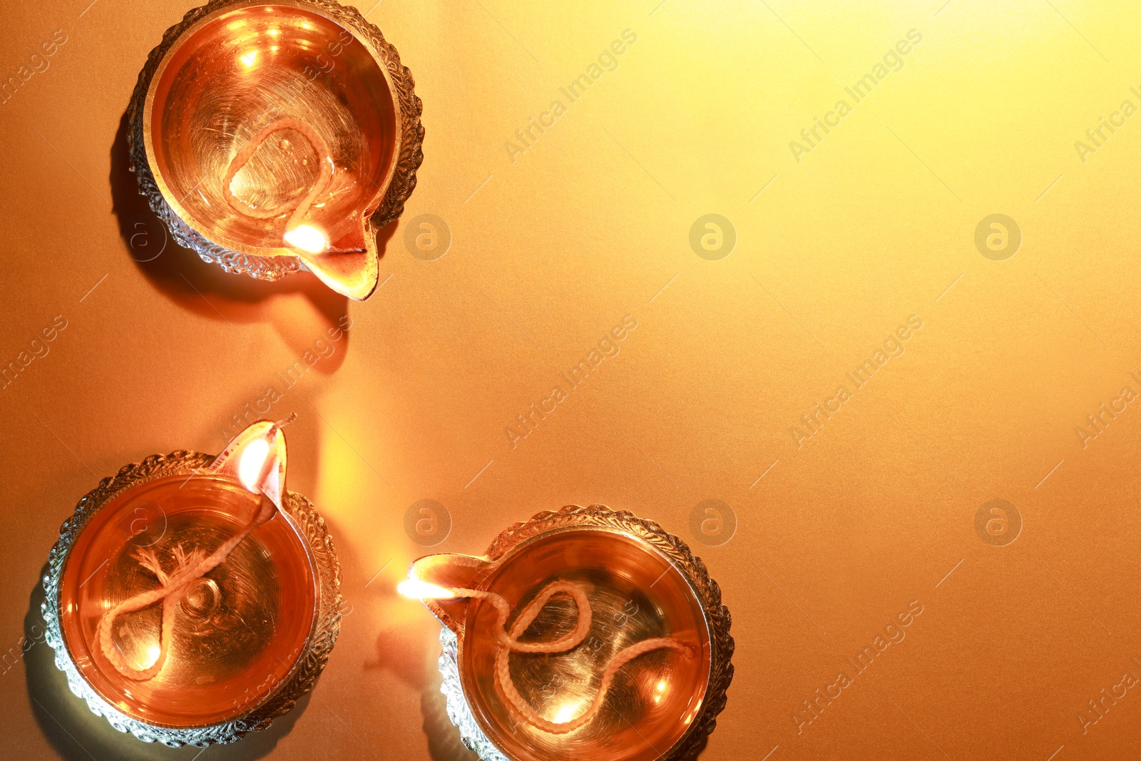 Photo of Diwali celebration. Diya lamps on orange background, flat lay. Space for text