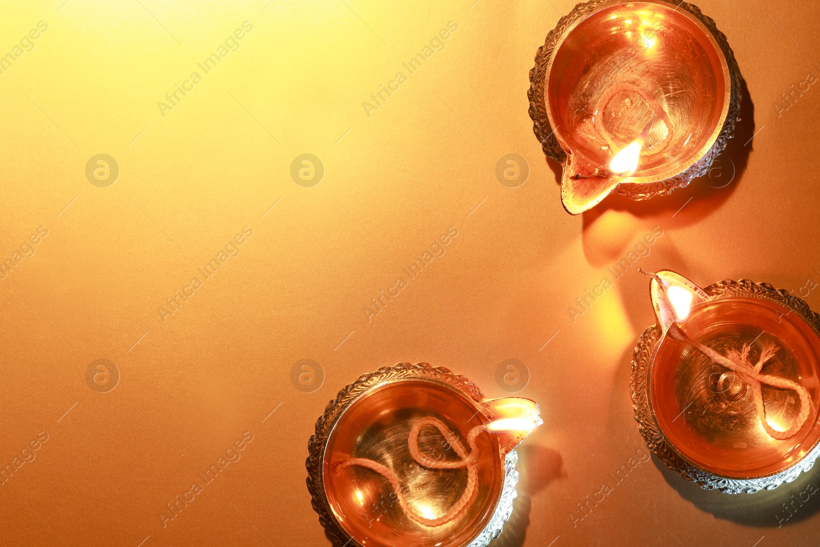 Photo of Diwali celebration. Diya lamps on orange background, flat lay. Space for text