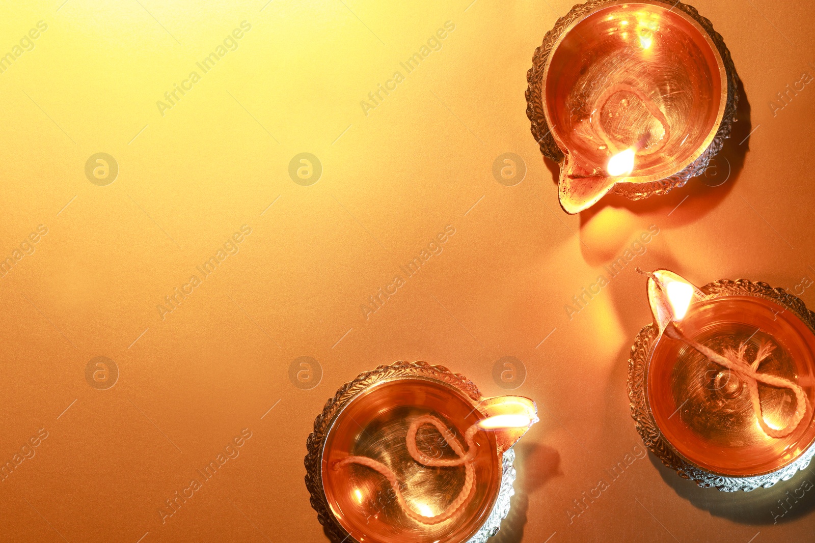 Photo of Diwali celebration. Diya lamps on orange background, flat lay. Space for text