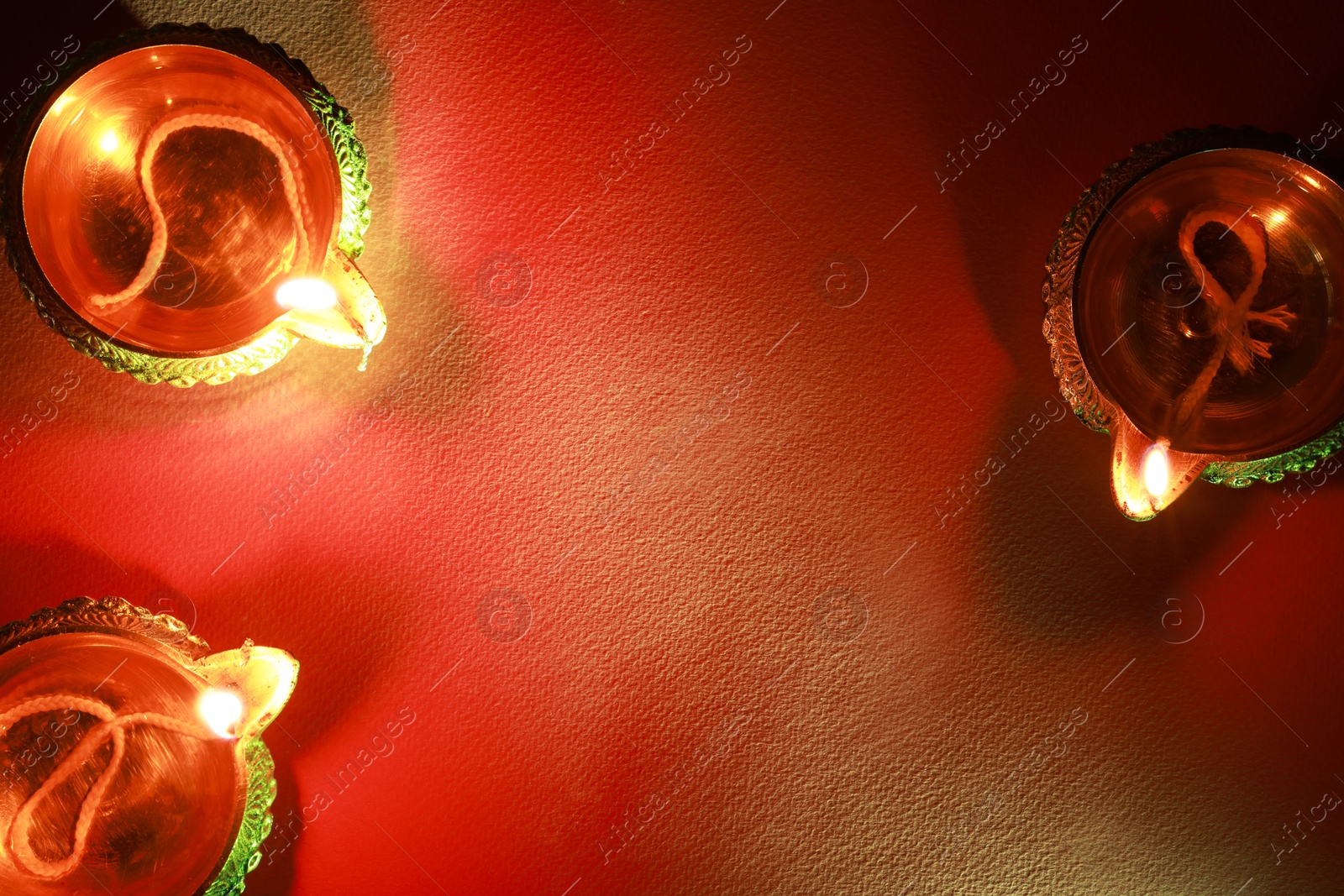 Photo of Diwali celebration. Diya lamps on red background, flat lay. Space for text