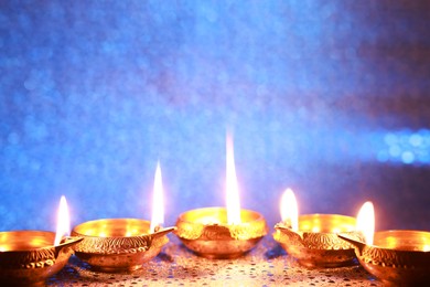 Photo of Diwali celebration. Diya lamps on color background. Space for text