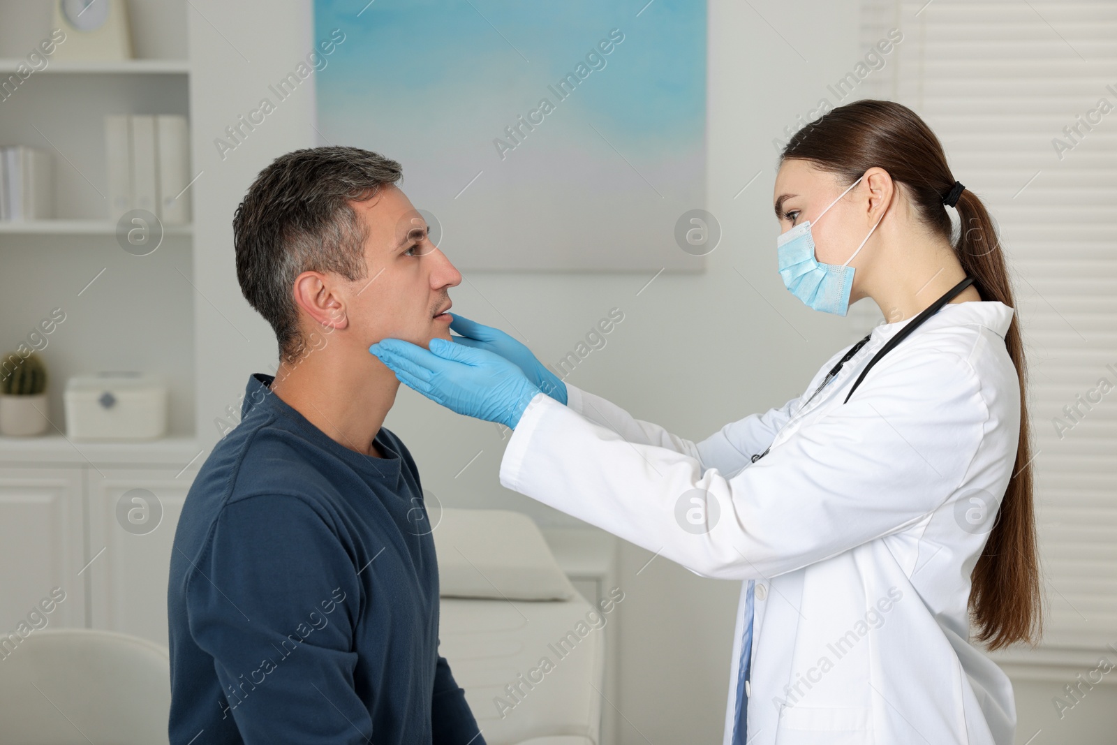 Photo of Doctor examining man's throat in clinic during appointment