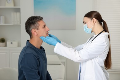 Photo of Doctor examining man's throat in clinic during appointment