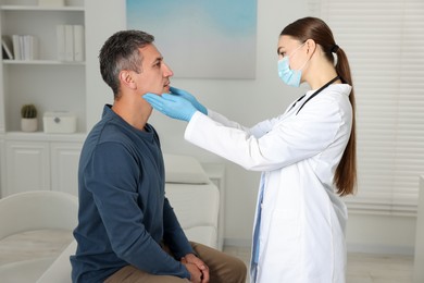 Photo of Doctor examining man's throat in clinic during appointment