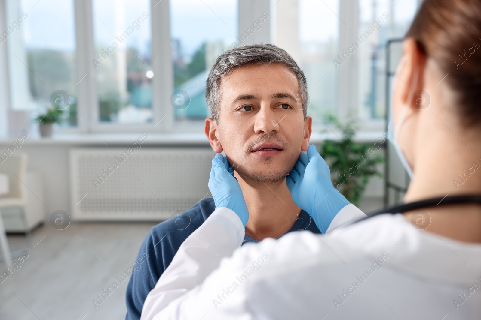 Photo of Doctor examining man's throat in clinic during appointment